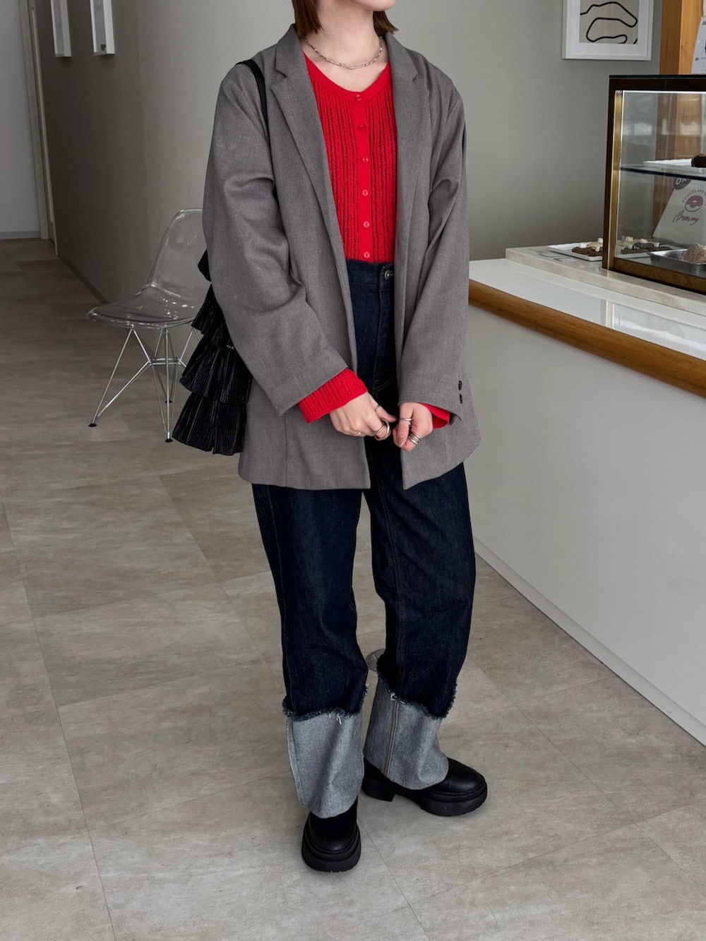 グレー系のテーラードジャケット、ブルー系のデニムパンツ、レッド系のカーディガン/ボレロを着用したレディースの冬コーディネートの2枚目の写真