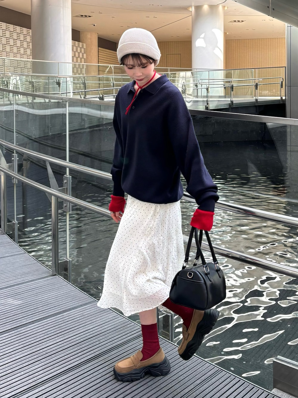 ホワイト系のスカート、グレー系のニット/セーター、ベージュ系のローファーを着用したレディースの冬コーディネートの2枚目の写真