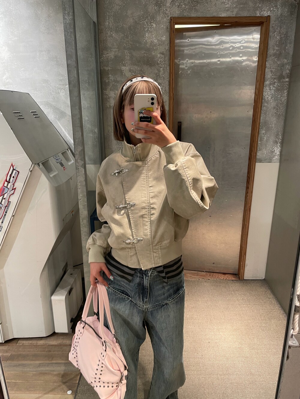 ホワイト系のブルゾン、ブルー系のデニムパンツ、ピンク系のショルダーバッグを着用したレディースの冬コーディネートの3枚目の写真