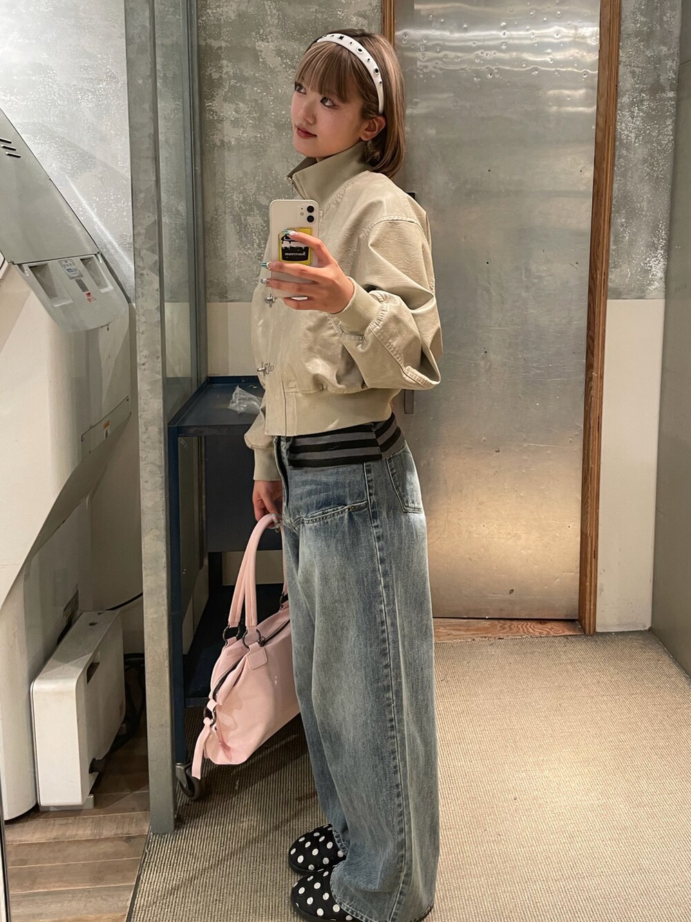 ホワイト系のブルゾン、ブルー系のデニムパンツ、ピンク系のショルダーバッグを着用したレディースの冬コーディネートの2枚目の写真