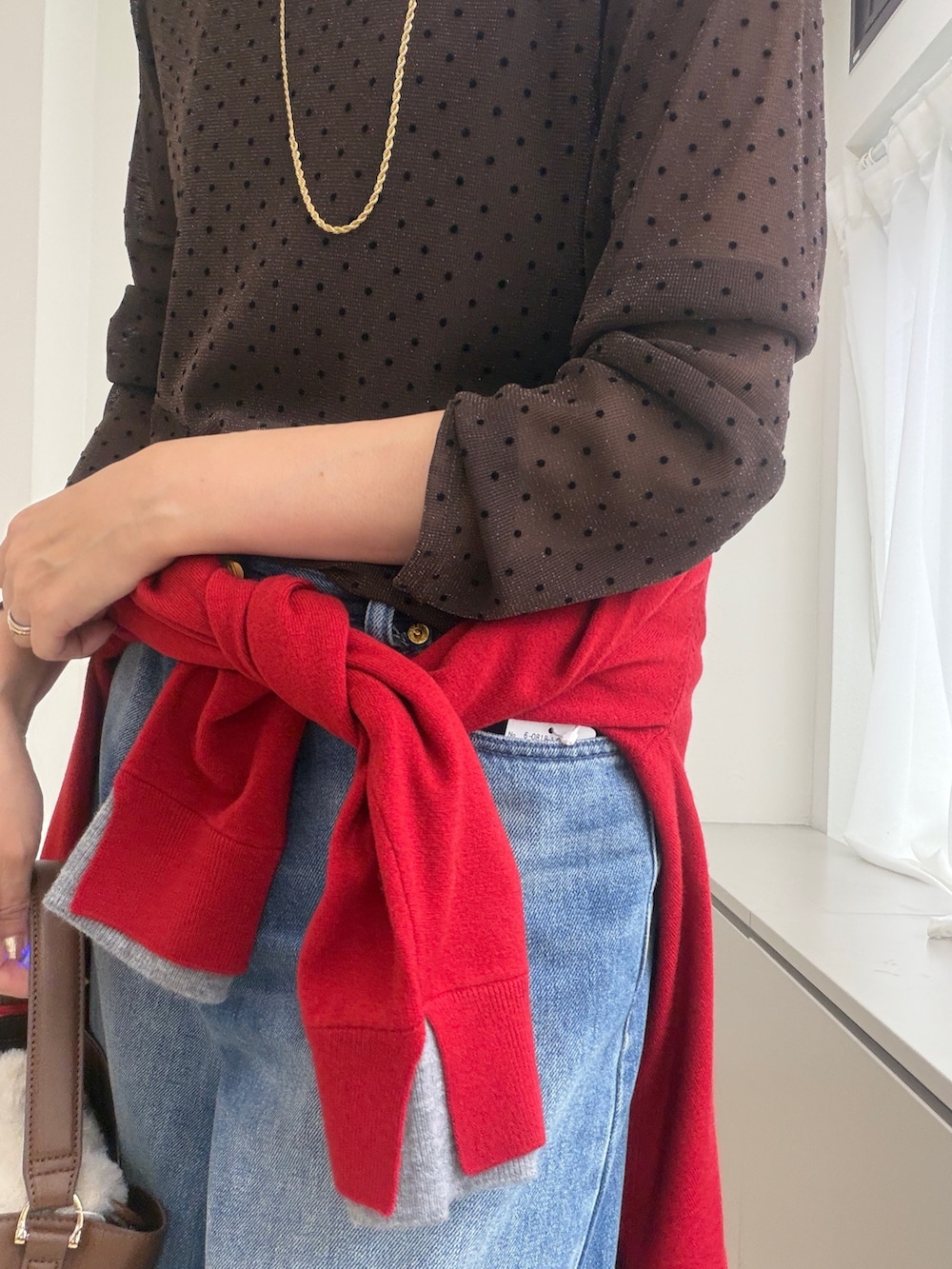 ブラウン系のTシャツ/カットソー、レッド系のカーディガン/ボレロ、ゴールド系のイヤリングを着用したレディースの秋コーディネートの5枚目の写真