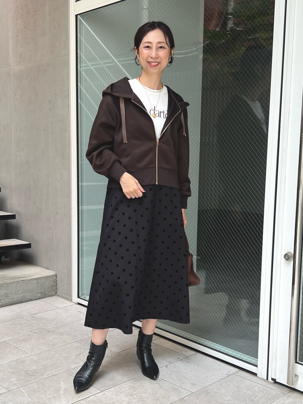 ブラウン系のスカート、ブラウン系のパーカーを着用したレディースの秋コーディネートの3枚目の写真