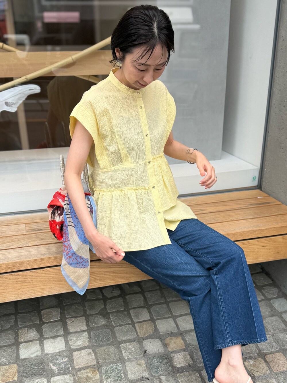 ブルー系のデニムパンツ、イエロー系のシャツ/ブラウス、ブルー系のストール/ショールを着用したレディースの春コーディネートの4枚目の写真