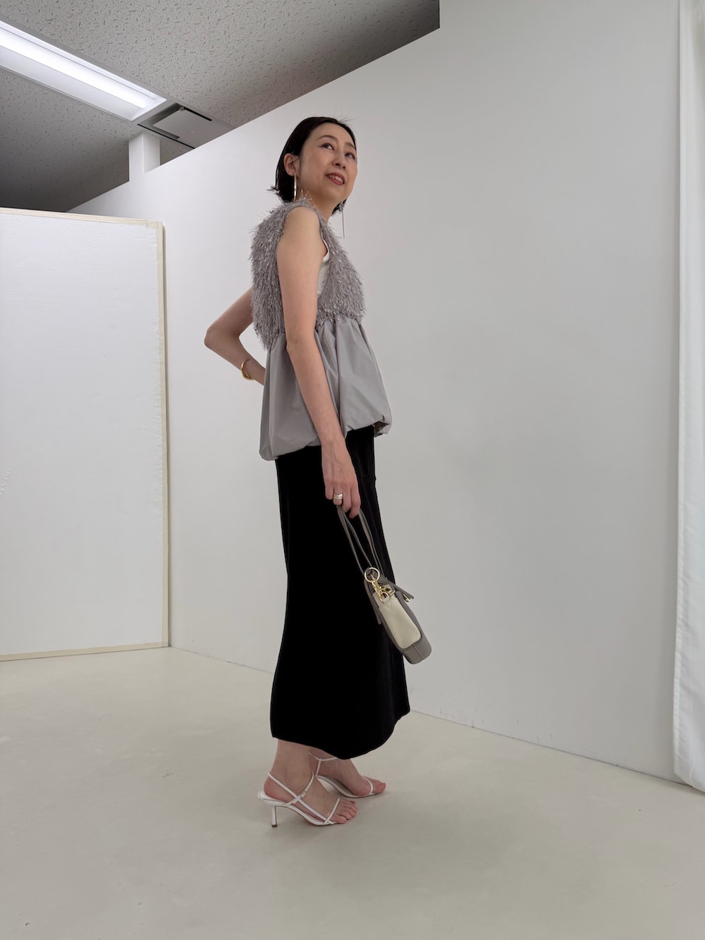 ブラック系のスカート、グレー系のシャツ/ブラウス、ホワイト系のTシャツ/カットソーを着用したレディースの春コーディネートの7枚目の写真