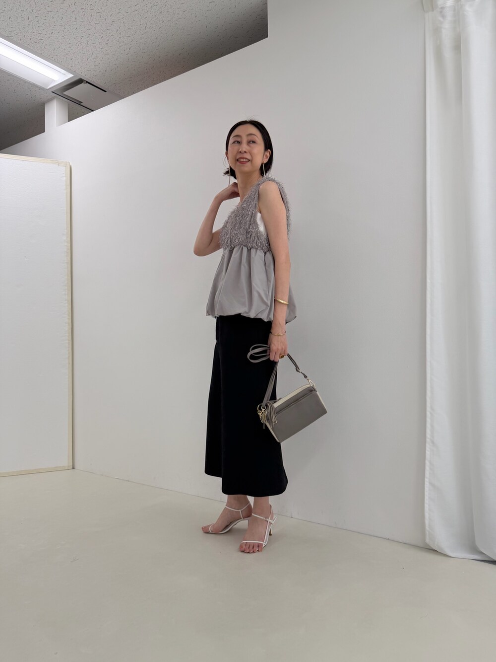 ブラック系のスカート、グレー系のシャツ/ブラウス、ホワイト系のTシャツ/カットソーを着用したレディースの春コーディネートの2枚目の写真