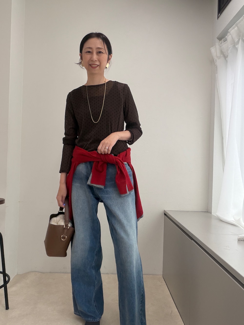 ブラウン系のTシャツ/カットソー、レッド系のカーディガン/ボレロ、ゴールド系のイヤリングを着用したレディースの秋コーディネートの2枚目の写真