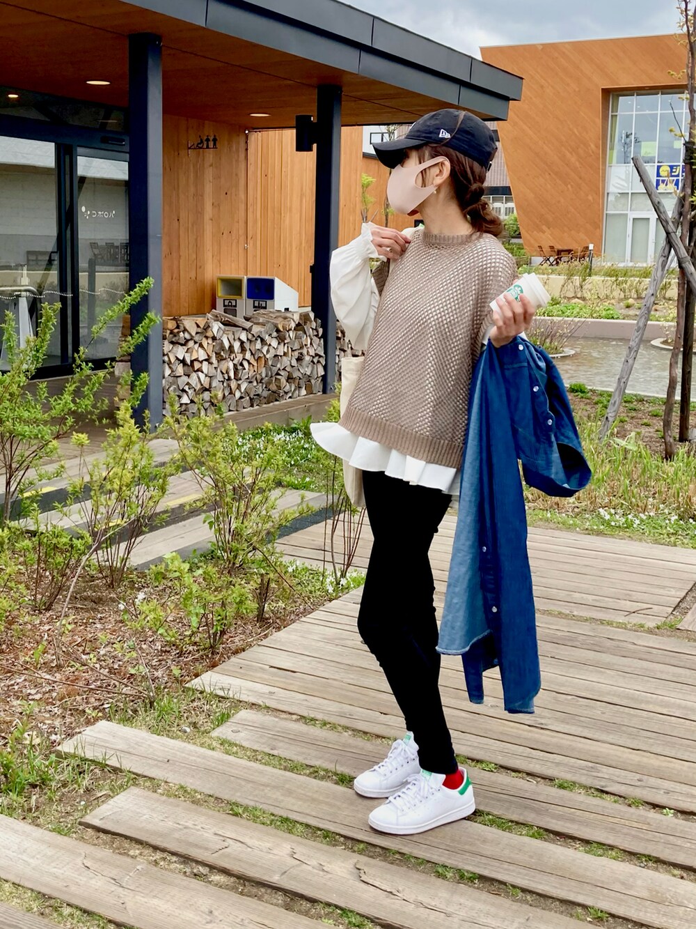 ブラック系のパンツ、ホワイト系のスニーカー、ブラウン系のベストを着用したレディースの春コーディネートの2枚目の写真