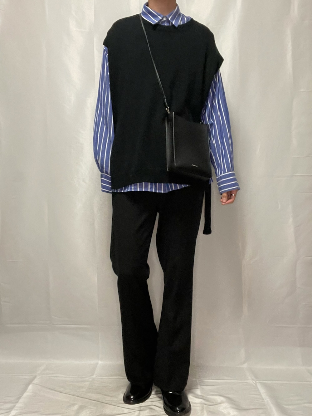 ブラック系のスラックス、ブラック系のブーツ、ブラック系のベストを着用したメンズの春コーディネートの2枚目の写真