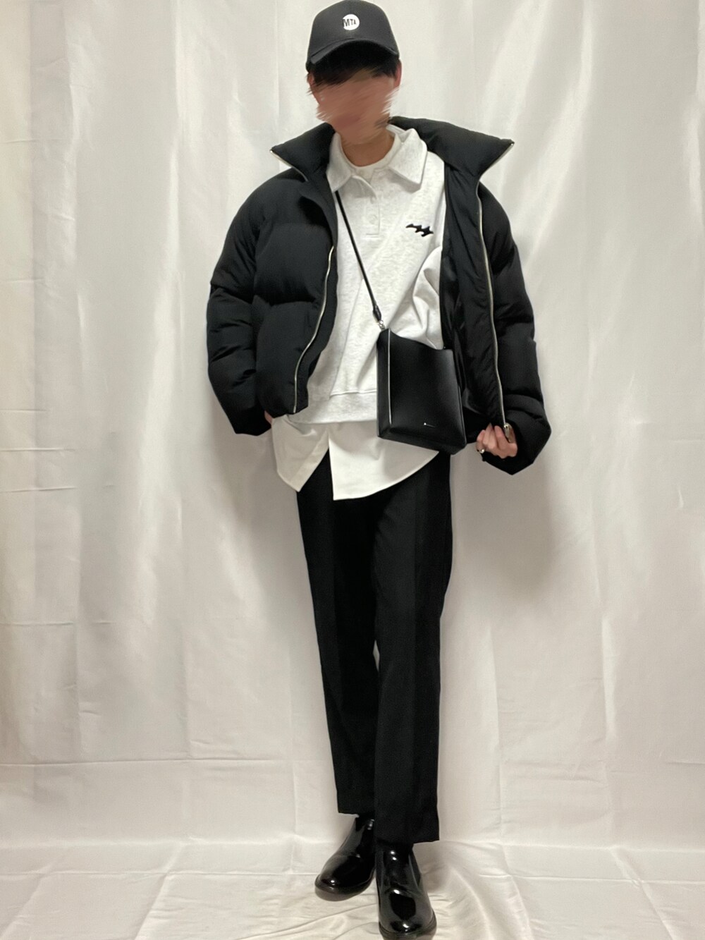 ブラック系のスラックス、ブラック系のブーツ、ホワイト系のトップスを着用したメンズの春コーディネートの2枚目の写真