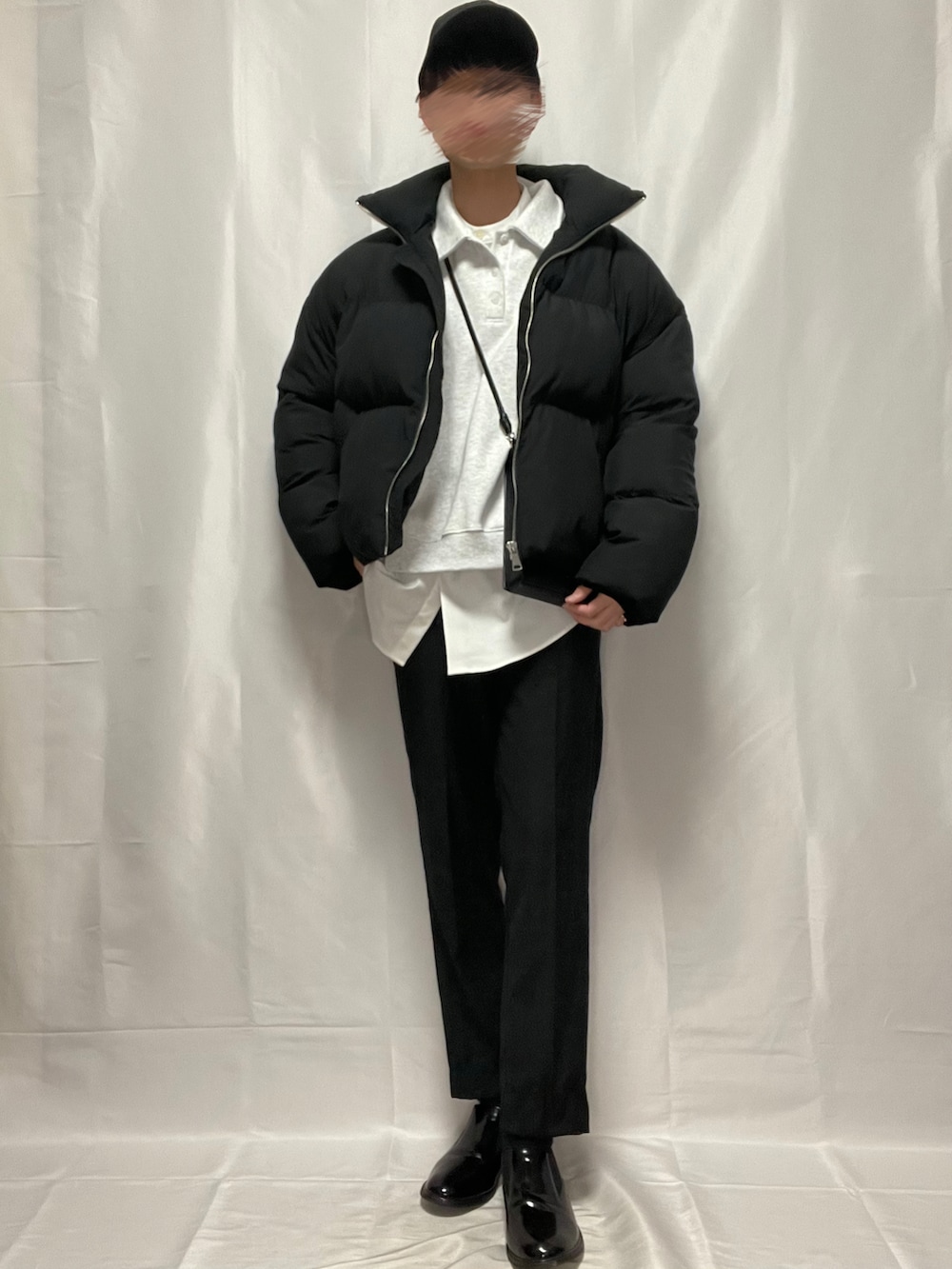 ブラック系のスラックス、ブラック系のブーツ、ホワイト系のトップスを着用したメンズの春コーディネートの3枚目の写真