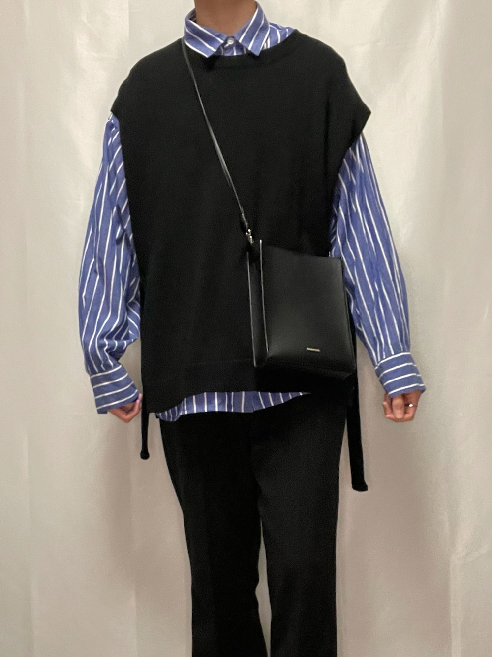 ブラック系のスラックス、ブラック系のブーツ、ブラック系のベストを着用したメンズの春コーディネートの4枚目の写真