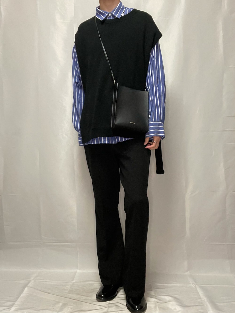 ブラック系のスラックス、ブラック系のブーツ、ブラック系のベストを着用したメンズの春コーディネートの3枚目の写真