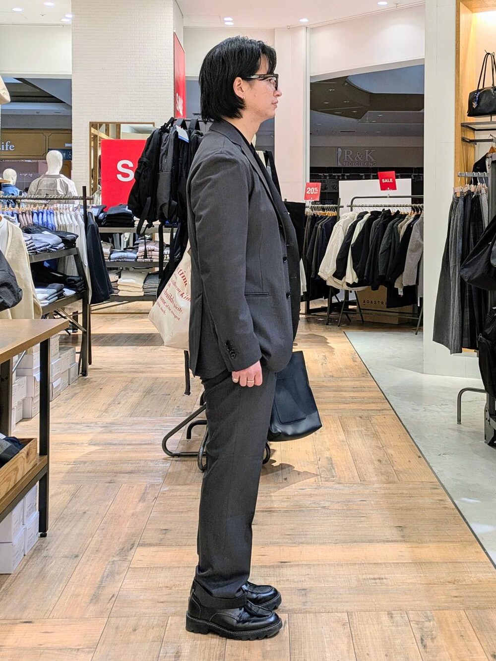 グレー系のテーラードジャケット、グレー系のスラックス、ブラック系のポロシャツを着用したメンズの冬コーディネートの2枚目の写真