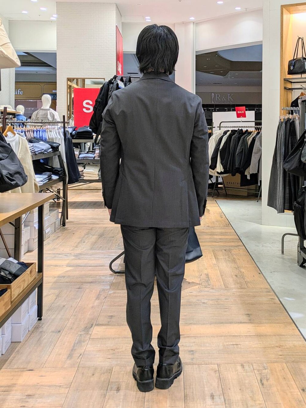 グレー系のテーラードジャケット、グレー系のスラックス、ブラック系のポロシャツを着用したメンズの冬コーディネートの3枚目の写真