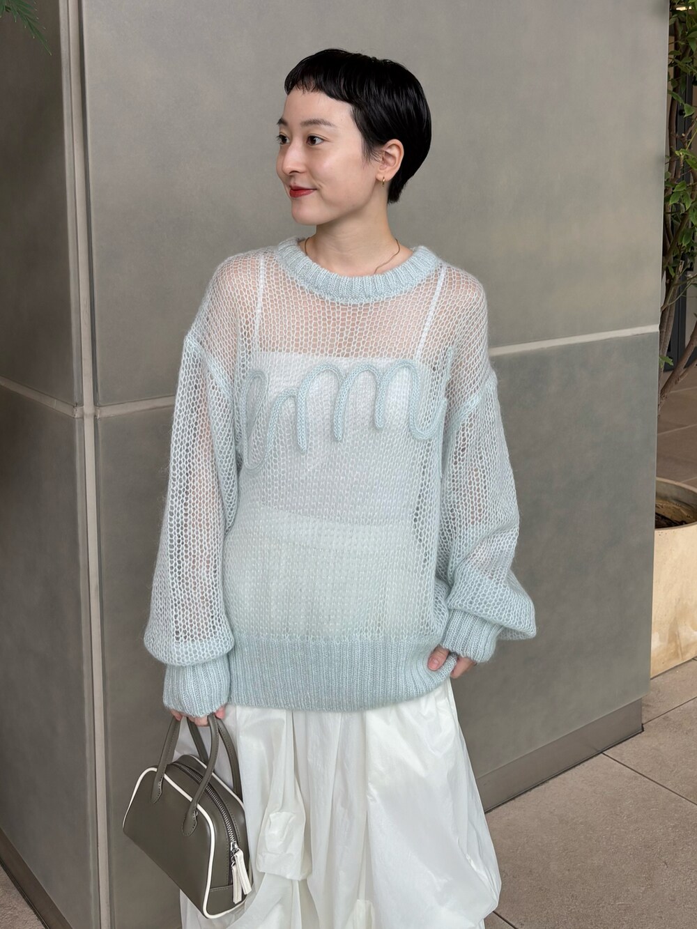 ブルー系のニット/セーター、ホワイト系のスカート、グリーン系のボストンバッグを着用したレディースの秋コーディネートの2枚目の写真