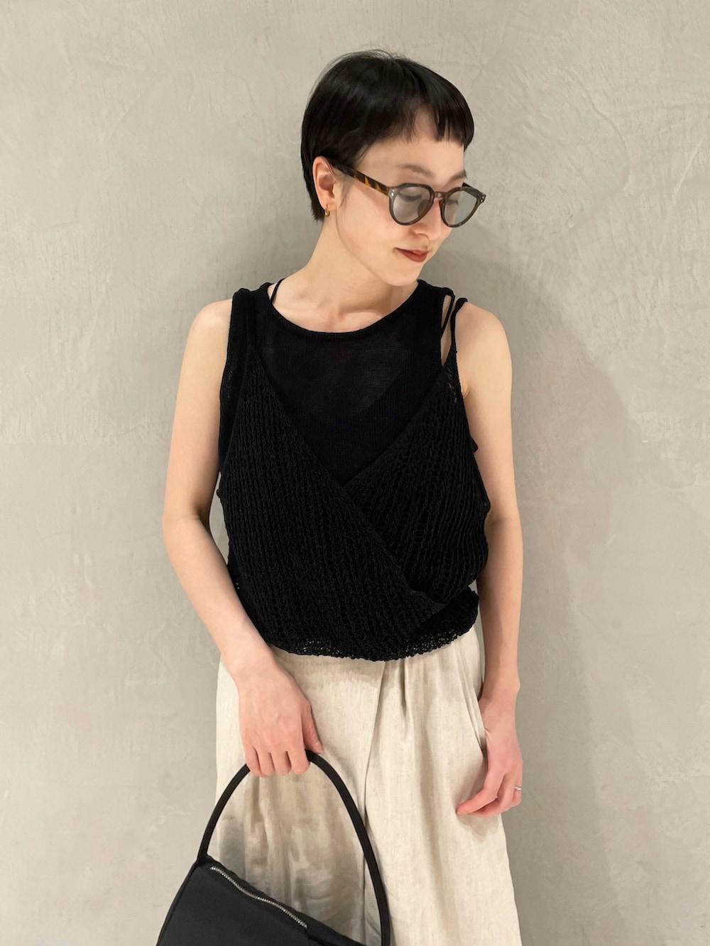 ブラック系のニット/セーター、ベージュ系のその他パンツ、ブラック系のハンドバッグを着用したレディースの春コーディネートの4枚目の写真