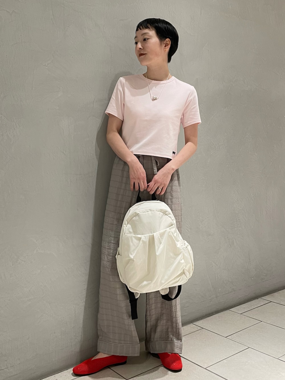 ピンク系のTシャツ/カットソー、グレー系のその他パンツ、ホワイト系のバックパック/リュックを着用したレディースの春コーディネートの2枚目の写真