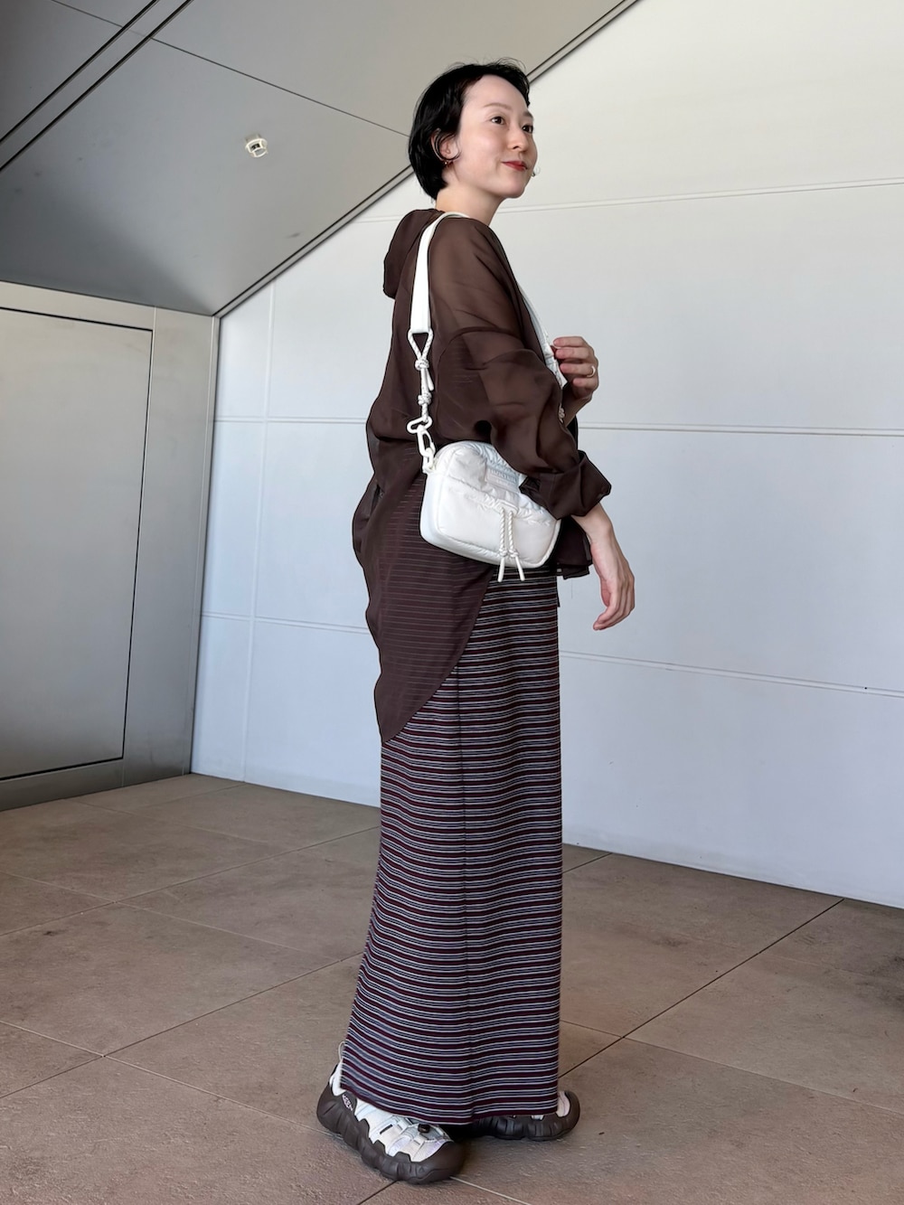 レッド系のワンピース、ホワイト系のショルダーバッグ、ベージュ系のサンダルを着用したレディースの夏コーディネートの4枚目の写真