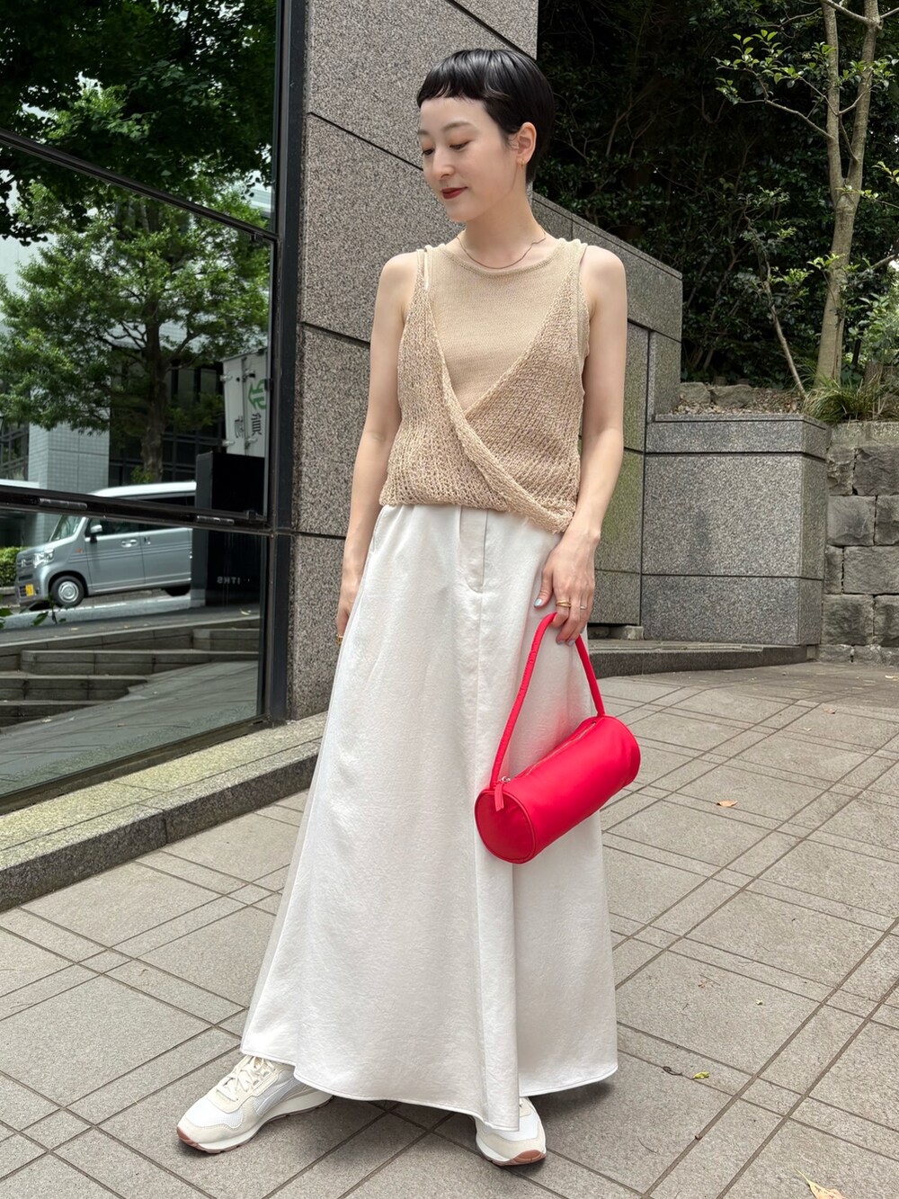 ベージュ系のニット/セーター、ベージュ系のスカート、レッド系のハンドバッグを着用したレディースの夏コーディネートの2枚目の写真