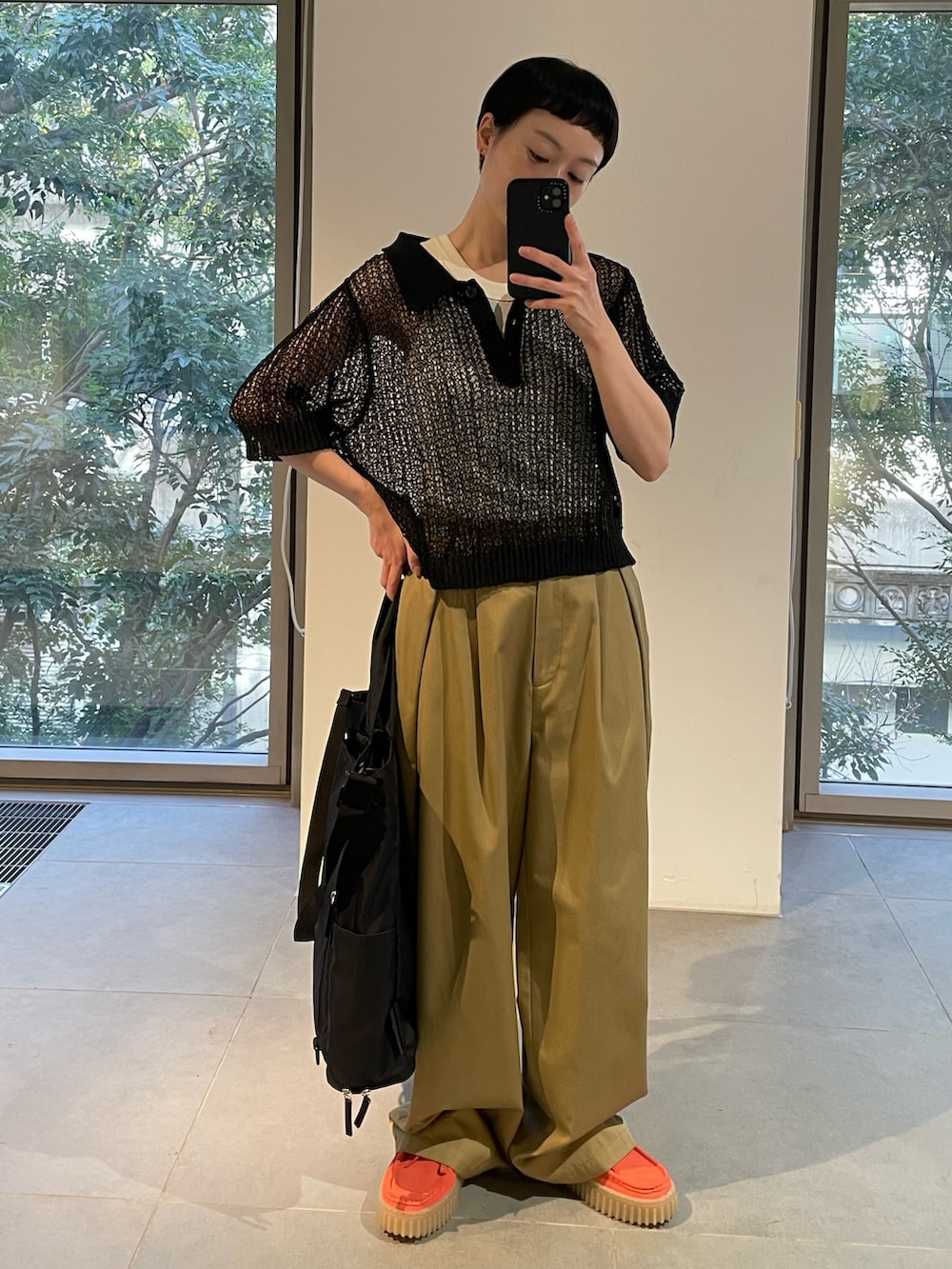 ホワイト系のタンクトップ、ブラック系のニット/セーター、ベージュ系のチノパンツを着用したレディースの春コーディネートの4枚目の写真