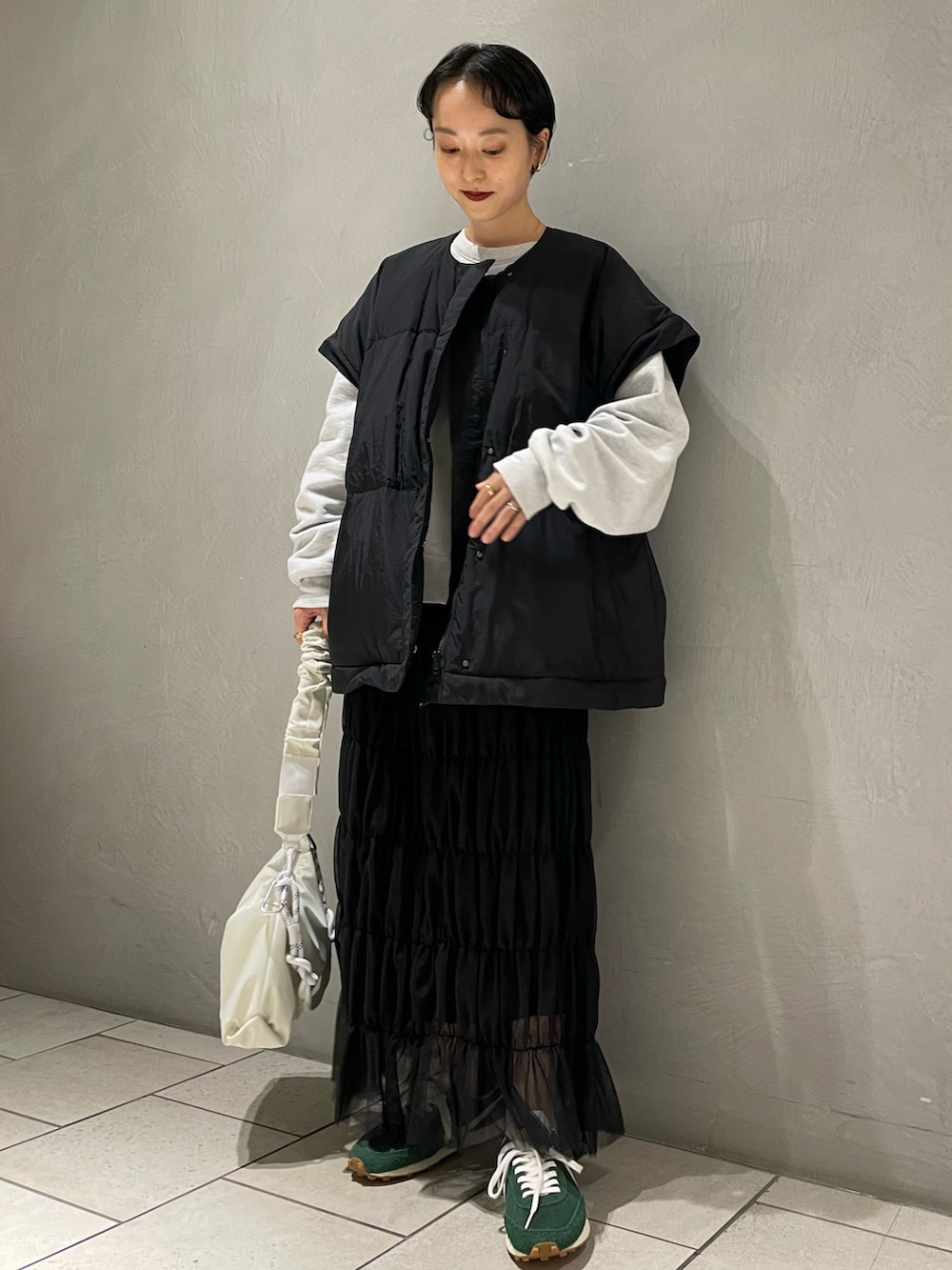 グレー系のスウェット、ブラック系のダウンジャケット/コート、ブラック系のスカートを着用したレディースの冬コーディネートの2枚目の写真