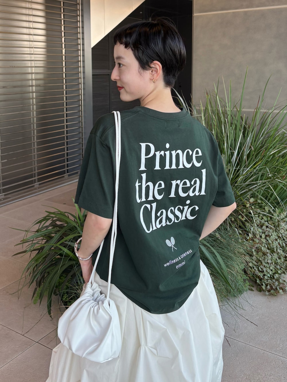 グリーン系のTシャツ/カットソー、ホワイト系のスカート、ブラウン系のスニーカーを着用したレディースの夏コーディネートの3枚目の写真