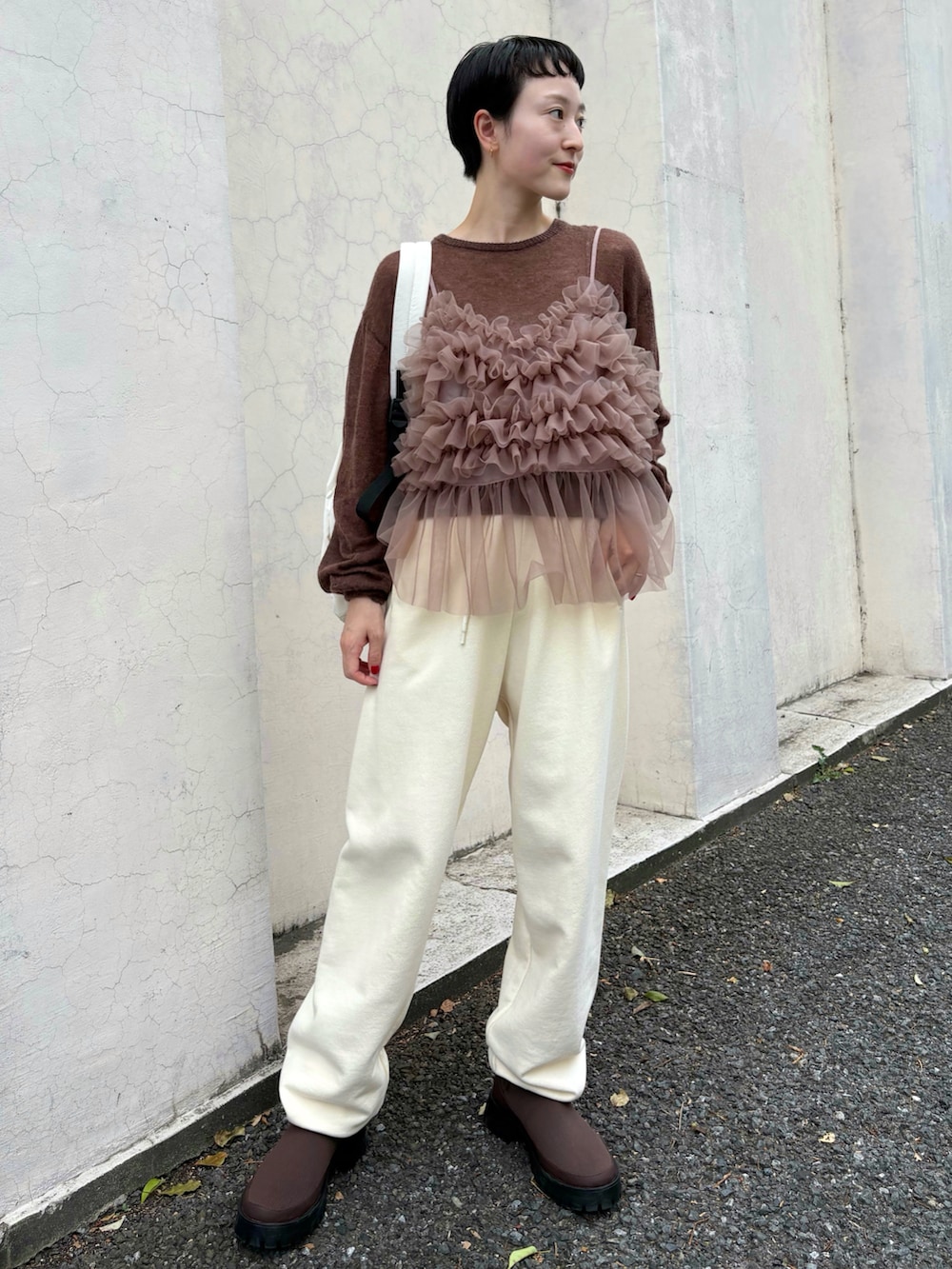 ブラウン系のニット/セーター、ブラウン系のTシャツ/カットソー、ホワイト系のスウェットパンツを着用したレディースの秋コーディネートの2枚目の写真