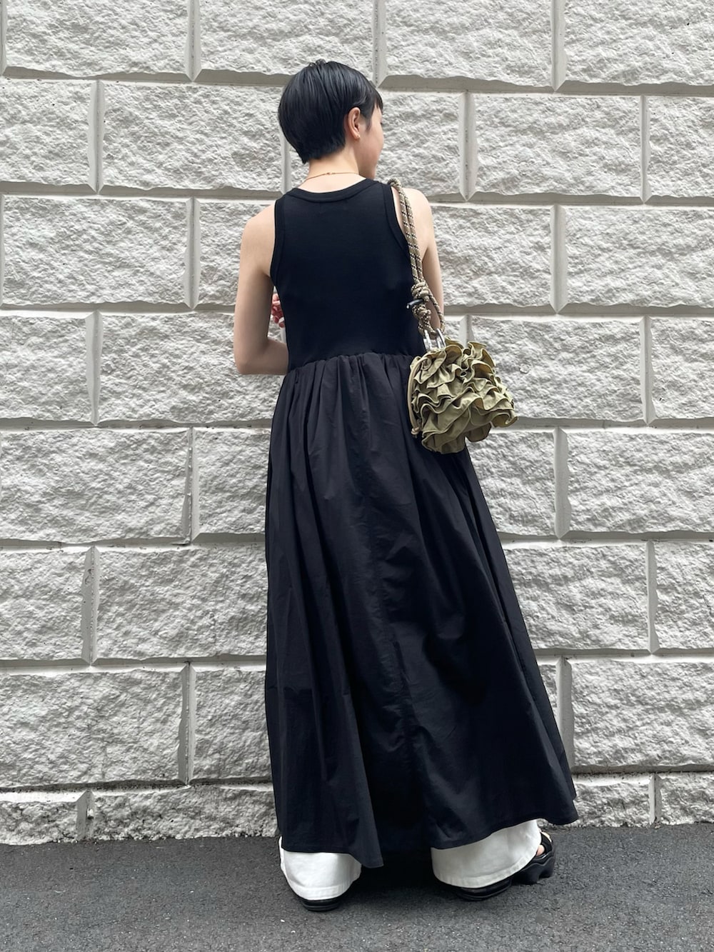 ブラック系のワンピース、グリーン系のショルダーバッグ、ホワイト系のデニムパンツを着用したレディースの夏コーディネートの2枚目の写真