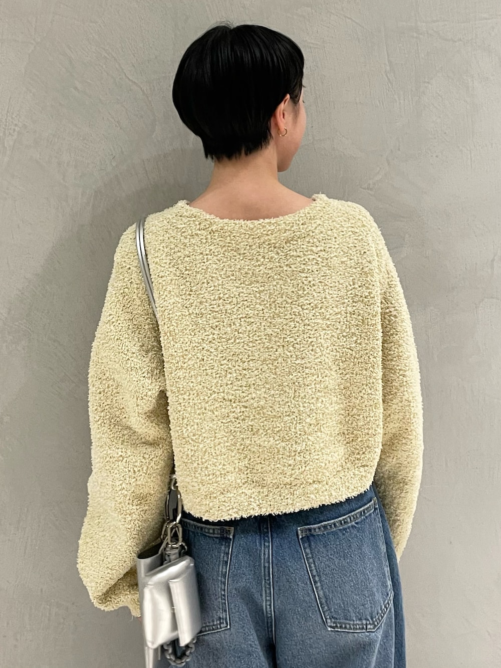 イエロー系のノーカラージャケット、シルバー系のショルダーバッグ、ブルー系のデニムパンツを着用したレディースの春コーディネートの4枚目の写真