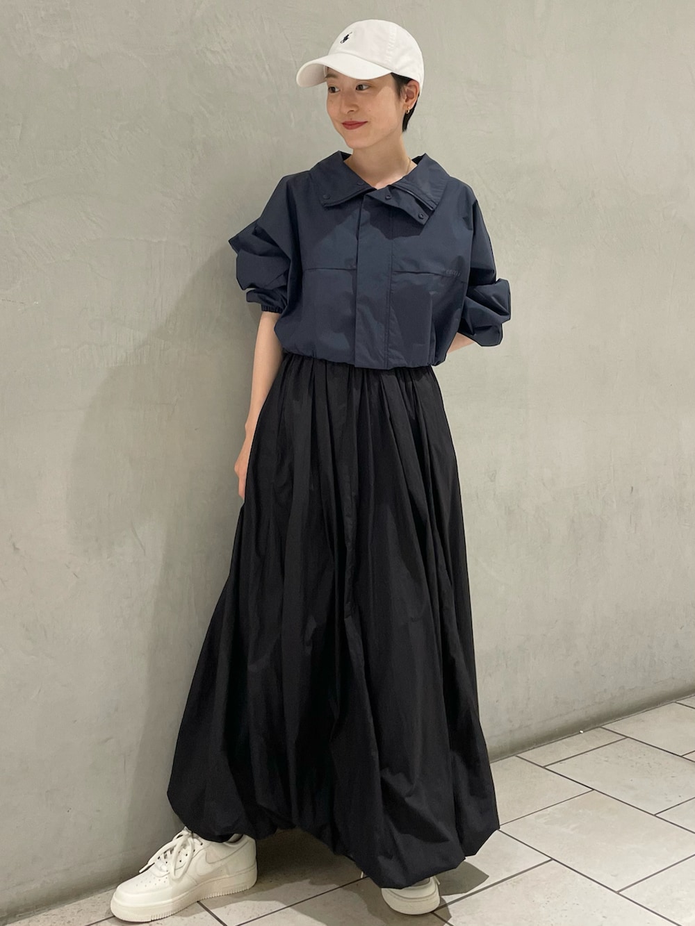 ブルー系のナイロンジャケット、ブラック系のスカート、ベージュ系のスニーカーを着用したレディースの春コーディネートの2枚目の写真