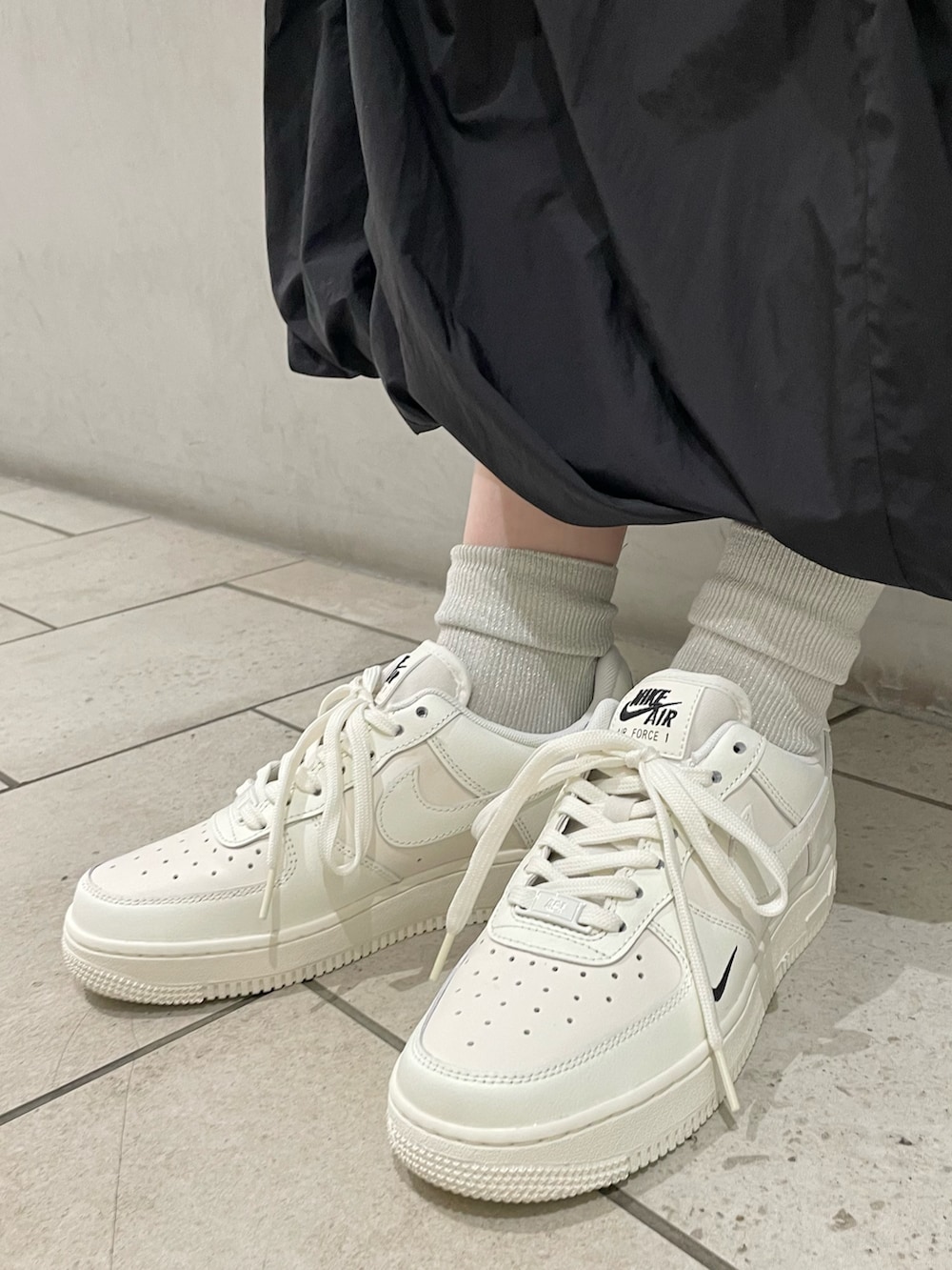 ブルー系のナイロンジャケット、ブラック系のスカート、ベージュ系のスニーカーを着用したレディースの春コーディネートの5枚目の写真