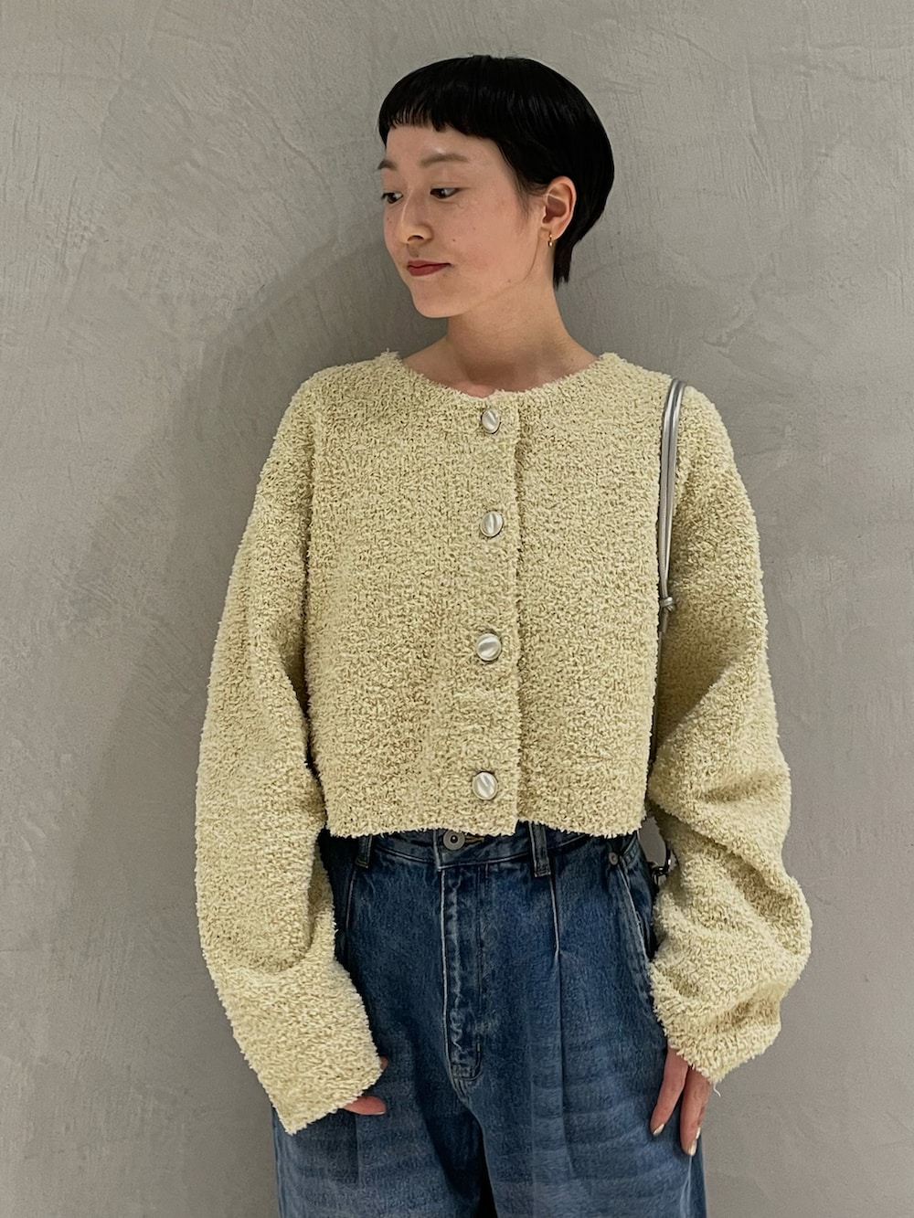 イエロー系のノーカラージャケット、シルバー系のショルダーバッグ、ブルー系のデニムパンツを着用したレディースの春コーディネートの3枚目の写真