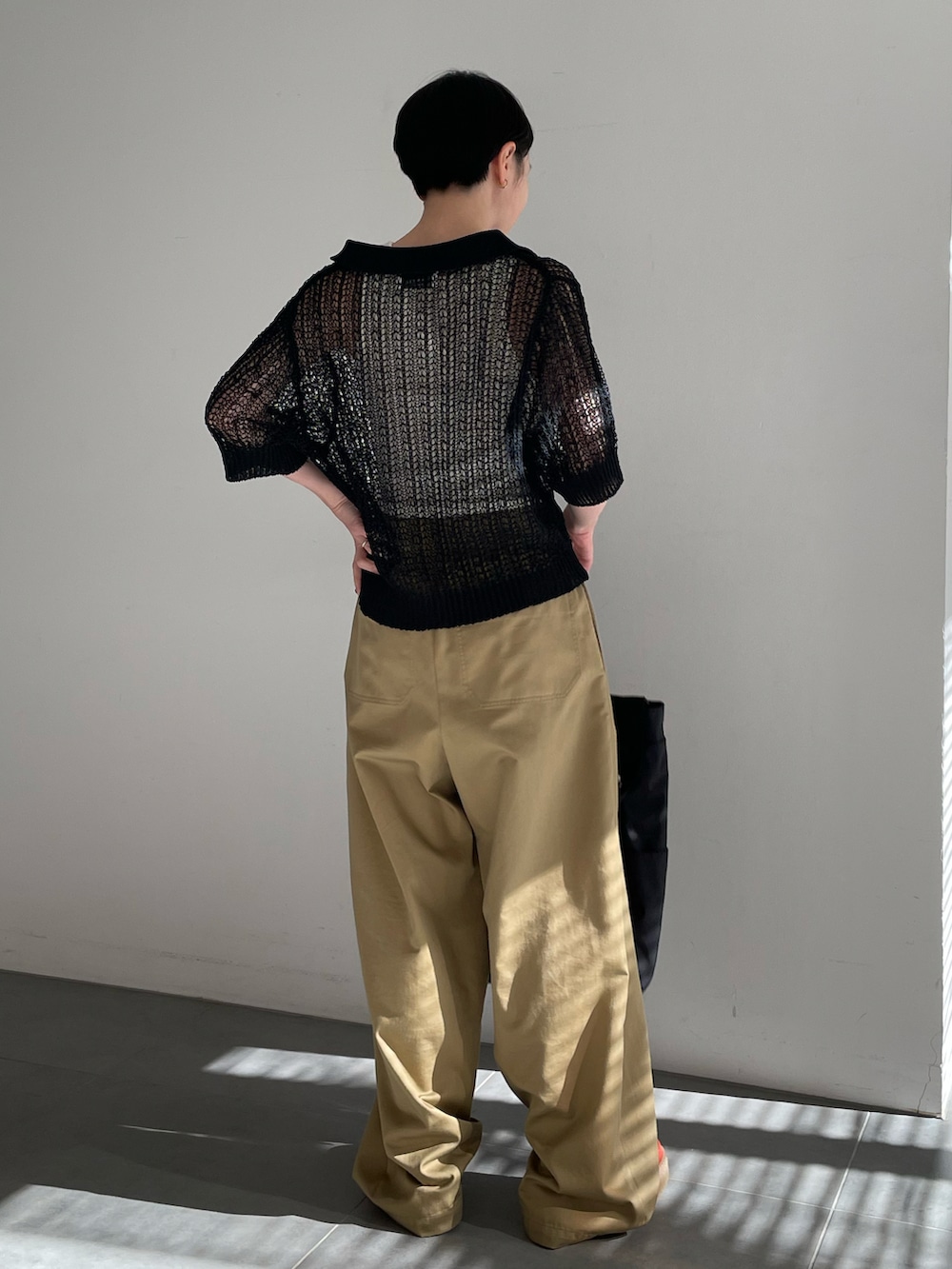 ホワイト系のタンクトップ、ブラック系のニット/セーター、ベージュ系のチノパンツを着用したレディースの春コーディネートの3枚目の写真