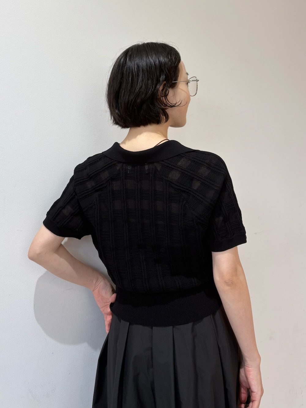 ブラック系のポロシャツ、ブラック系のスカート、ブラウン系のショルダーバッグを着用したレディースの夏コーディネートの3枚目の写真