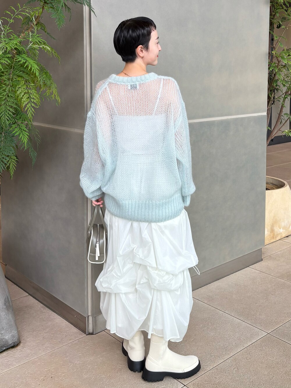 ブルー系のニット/セーター、ホワイト系のスカート、グリーン系のボストンバッグを着用したレディースの秋コーディネートの4枚目の写真