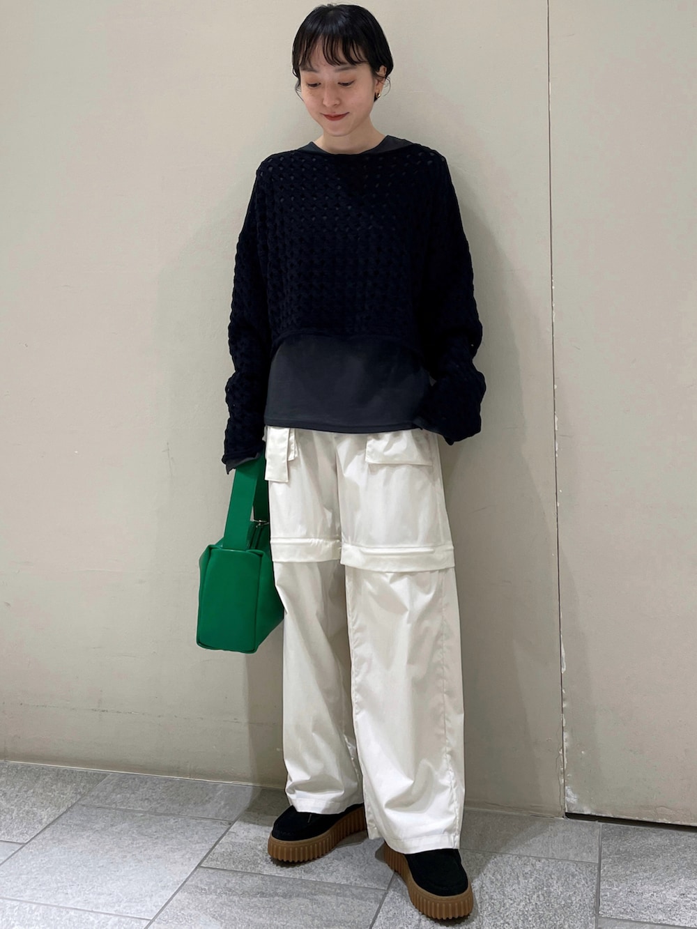 ホワイト系のカーゴパンツ、グレー系のTシャツ/カットソー、ブラック系のニット/セーターを着用したレディースの春コーディネートの2枚目の写真