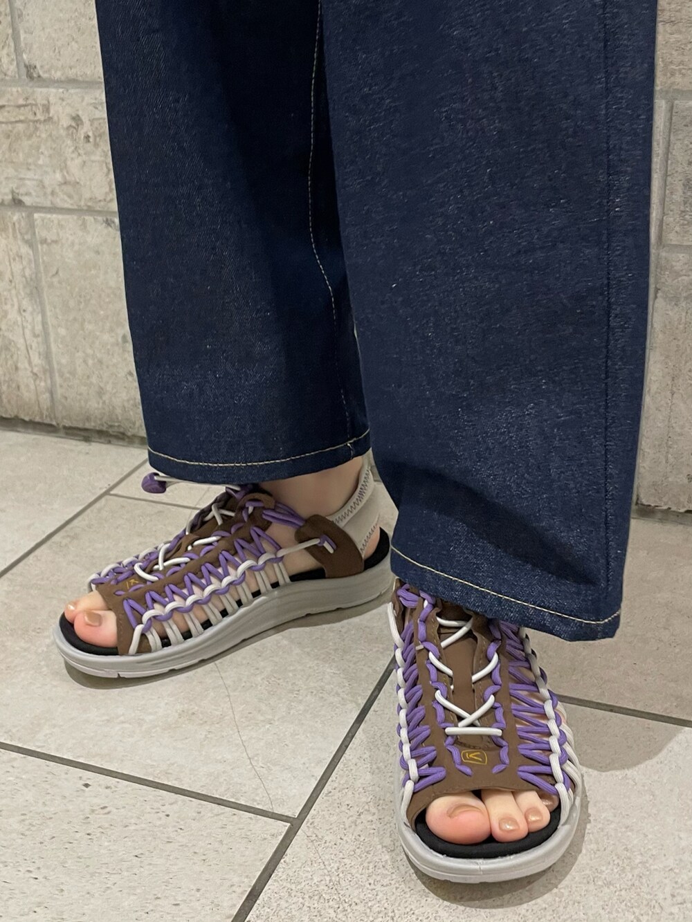 パープル系のニット/セーター、ブルー系のデニムパンツ、ブラウン系のサンダルを着用したレディースの春コーディネートの5枚目の写真