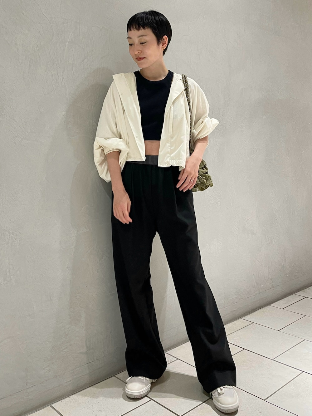 ブラック系のタンクトップ、ホワイト系のナイロンジャケット、ブラック系のスラックスを着用したレディースの夏コーディネートの2枚目の写真