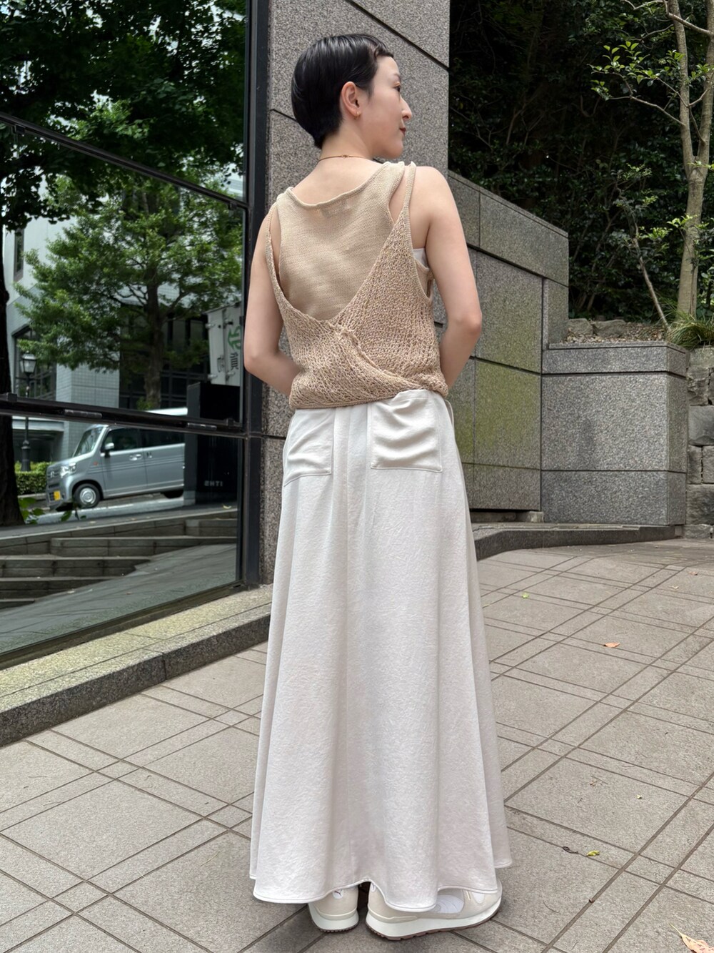 ベージュ系のニット/セーター、ベージュ系のスカート、レッド系のハンドバッグを着用したレディースの夏コーディネートの3枚目の写真