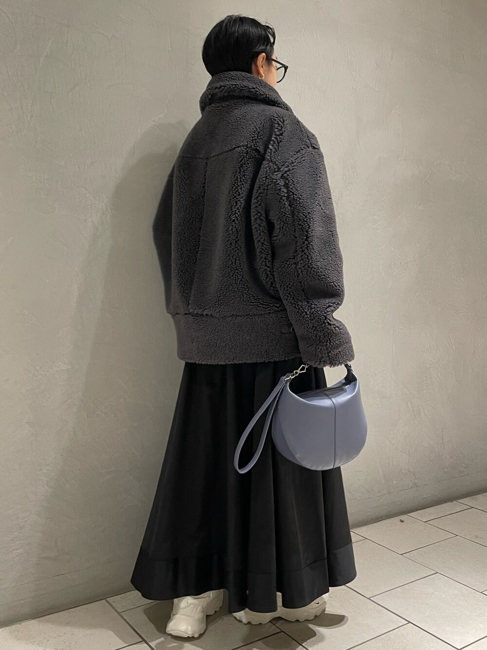 グレー系のブルゾン、ブラック系のスカート、ブルー系のショルダーバッグを着用したレディースの冬コーディネートの3枚目の写真