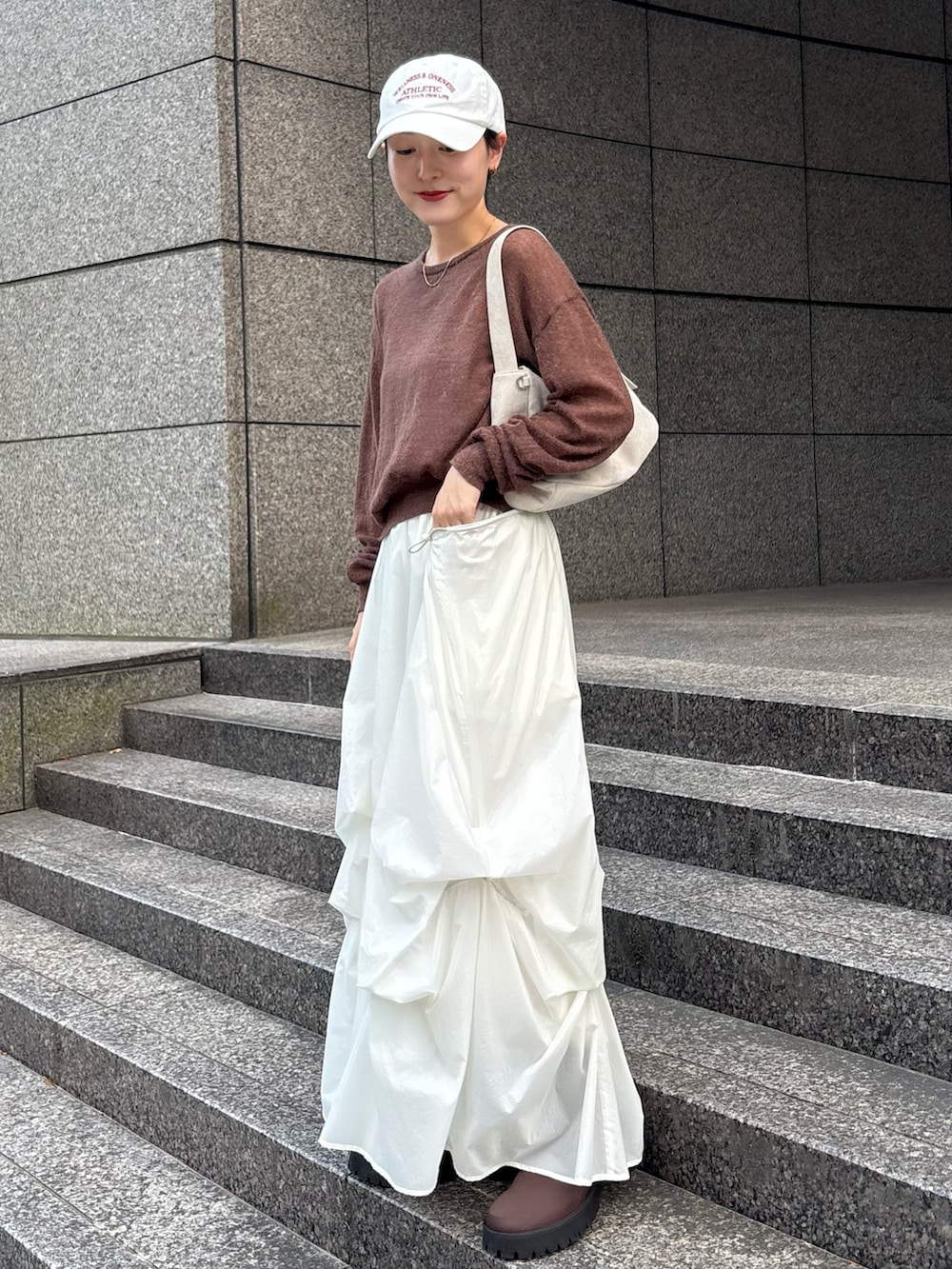 ブラウン系のニット/セーター、グレー系のショルダーバッグ、ホワイト系のスカートを着用したレディースの秋コーディネートの2枚目の写真