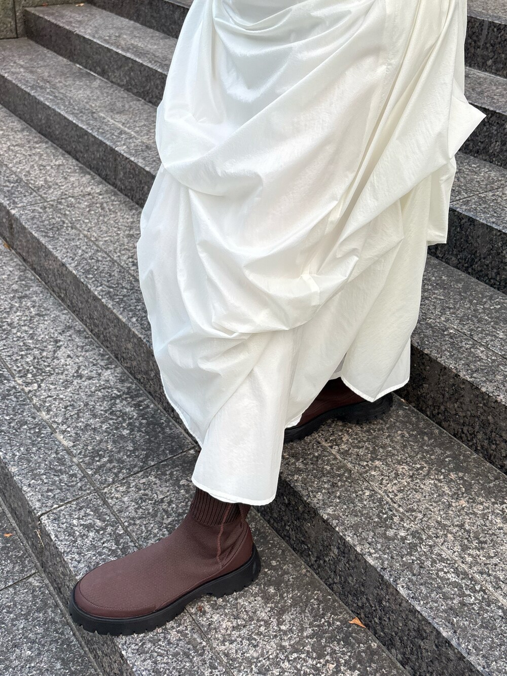 ブラウン系のニット/セーター、グレー系のショルダーバッグ、ホワイト系のスカートを着用したレディースの秋コーディネートの5枚目の写真