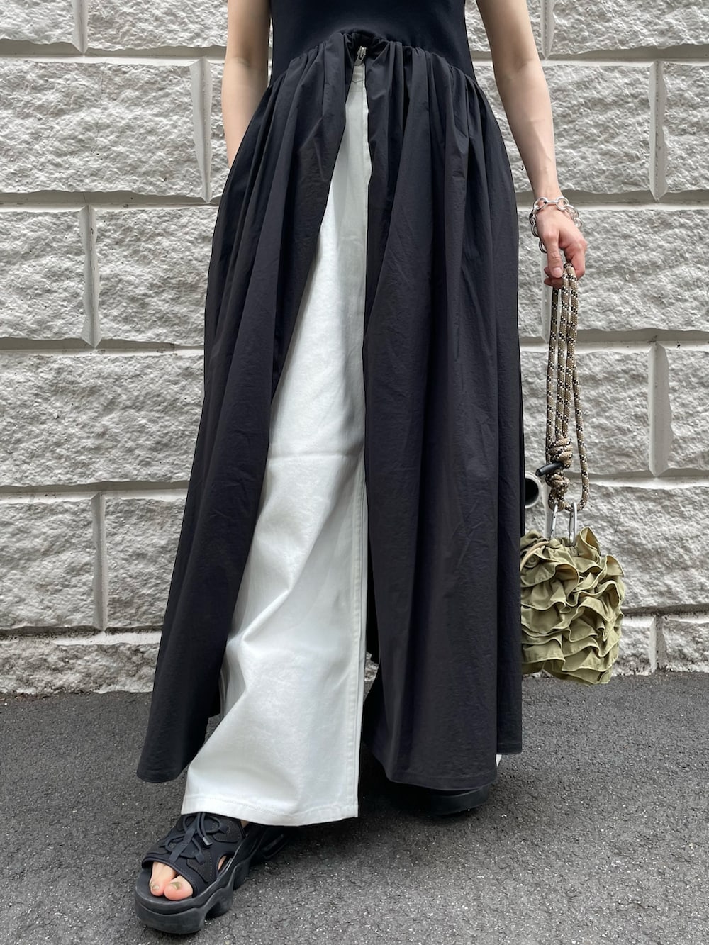 ブラック系のワンピース、グリーン系のショルダーバッグ、ホワイト系のデニムパンツを着用したレディースの夏コーディネートの5枚目の写真