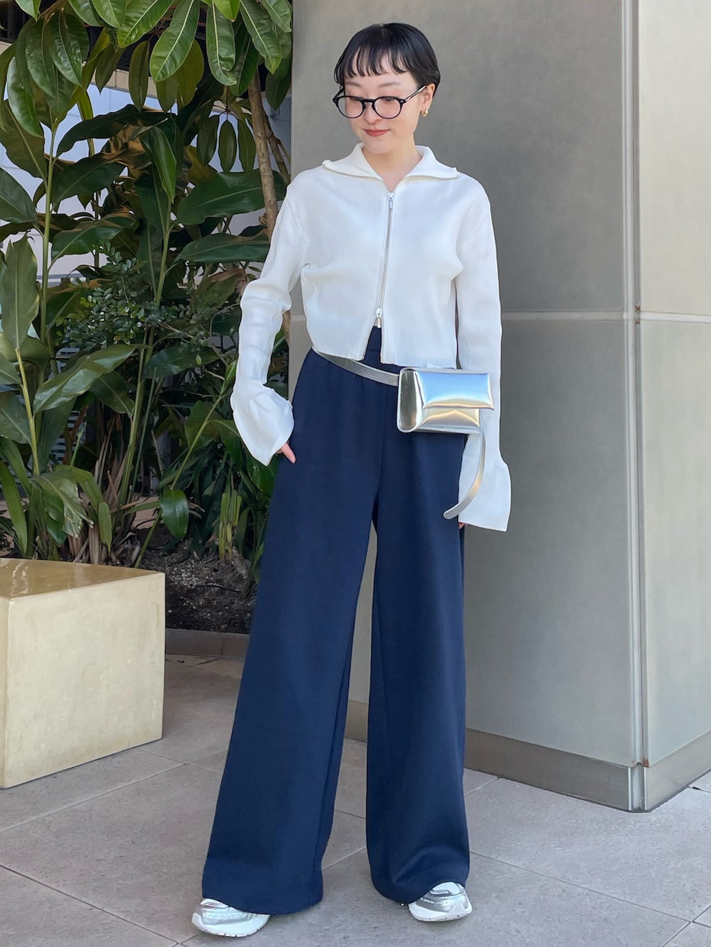 ホワイト系のニット/セーター、シルバー系のボディバッグ/ウエストポーチ、ブルー系のスウェットパンツを着用したレディースの冬コーディネートの2枚目の写真