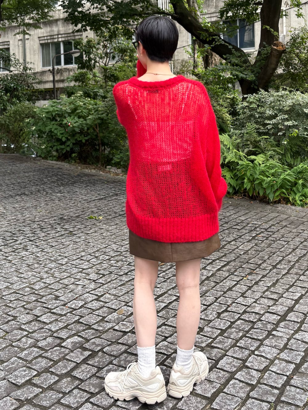 ブラウン系のブルゾン、レッド系のニット/セーター、ブラウン系のスカートを着用したレディースの夏コーディネートの3枚目の写真