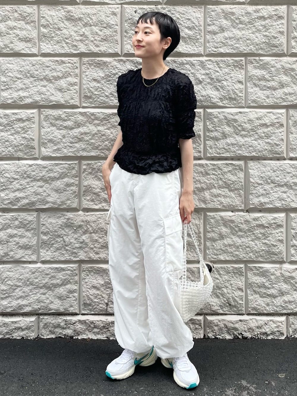 ブラック系のTシャツ/カットソー、ホワイト系のその他パンツ、その他のハンドバッグを着用したレディースの春コーディネートの2枚目の写真