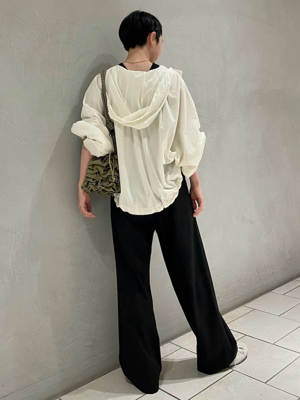 ブラック系のタンクトップ、ホワイト系のナイロンジャケット、ブラック系のスラックスを着用したレディースの夏コーディネートの3枚目の写真