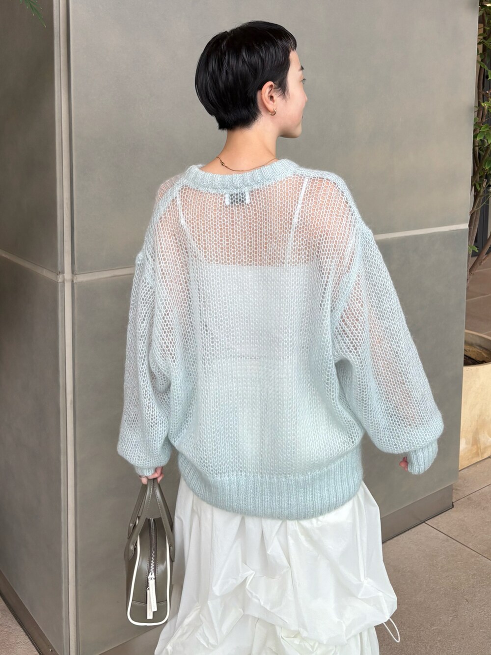 ブルー系のニット/セーター、ホワイト系のスカート、グリーン系のボストンバッグを着用したレディースの秋コーディネートの3枚目の写真