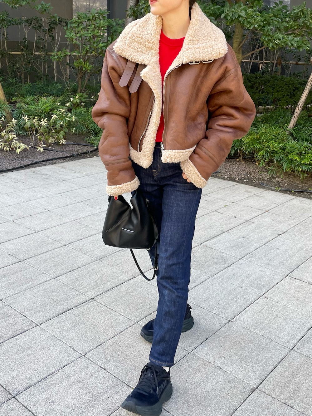 レッド系のニット/セーター、ブラック系のショルダーバッグ、ブラック系のスニーカーを着用したレディースの冬コーディネートの2枚目の写真