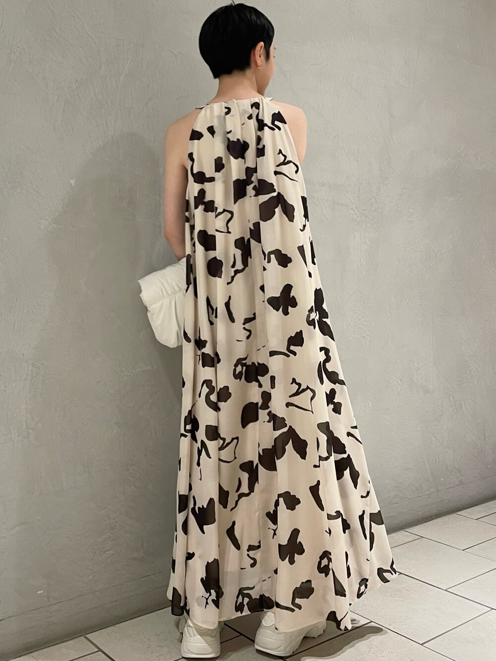 ベージュ系のワンピース、ホワイト系のトートバッグ、ホワイト系のサンダルを着用したレディースの夏コーディネートの2枚目の写真